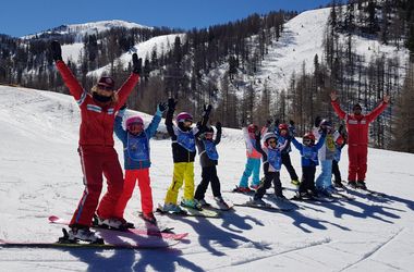 Enfants les bras en l'air sur leurs skis à Isola 2000